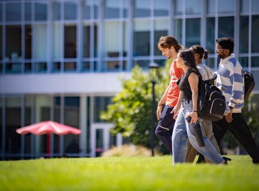 Four RCBC student models walking across the quad smiling