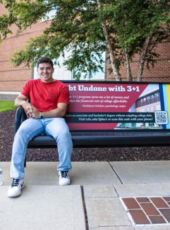 Student model Michael Caulder sits on a bench on campus.