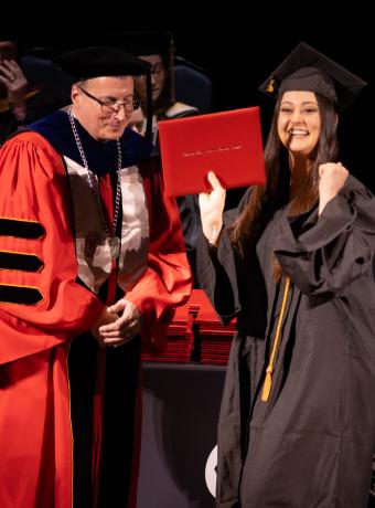 An RCBC graduate celebrates at commencement with her diploma.