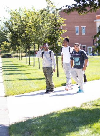 Three students walk together through the quad.