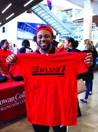 A student smiles with a 3+1 t-shirt on 3+1 day in the SSC.