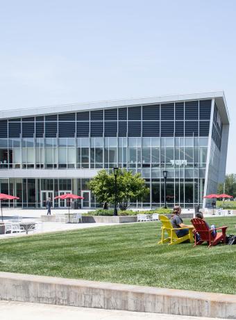 Four RCBC students sit on the quad outside the SSC on BOLD colored chairs