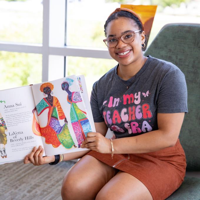 RCBC Education student smiling while holding an open book