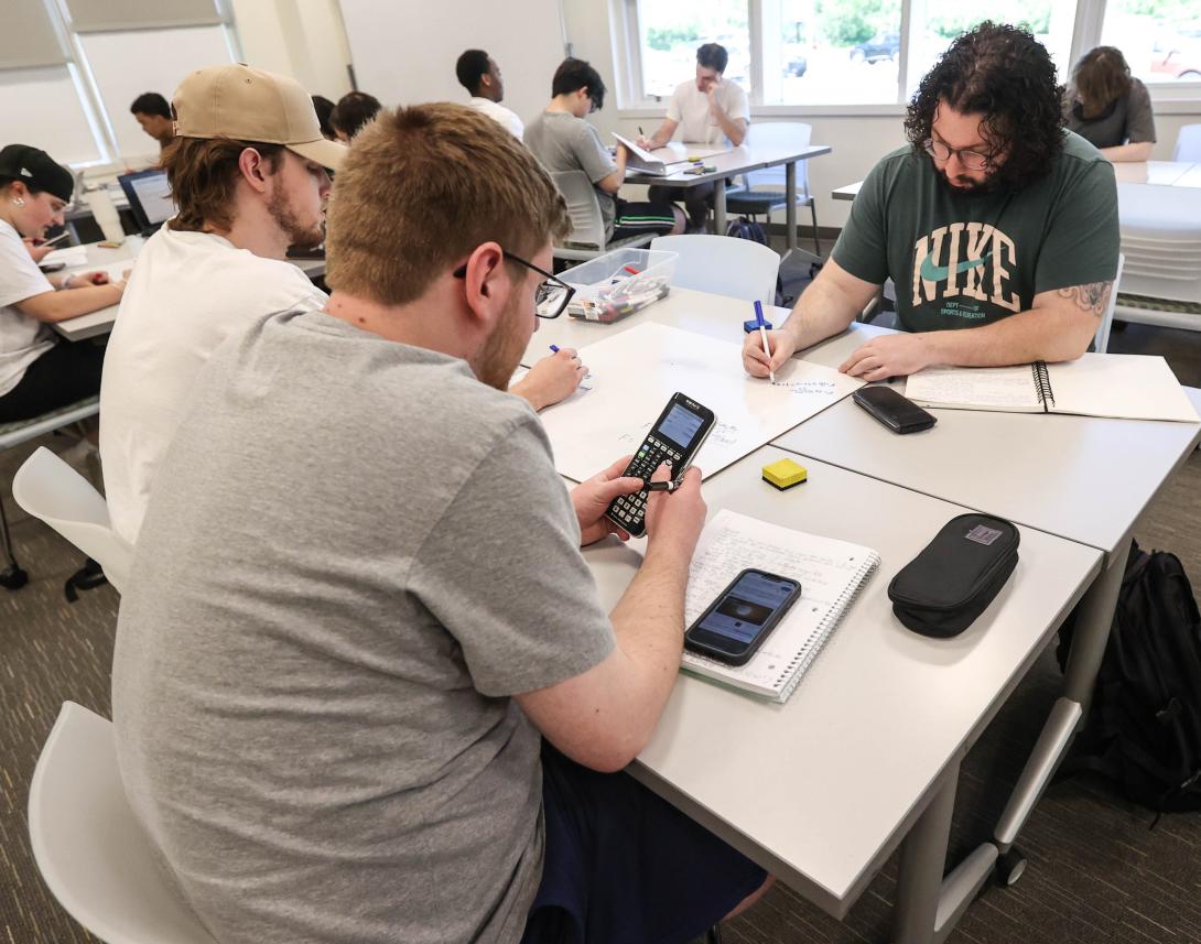 RCBC students work together on a problem in class with calculators and white boards.